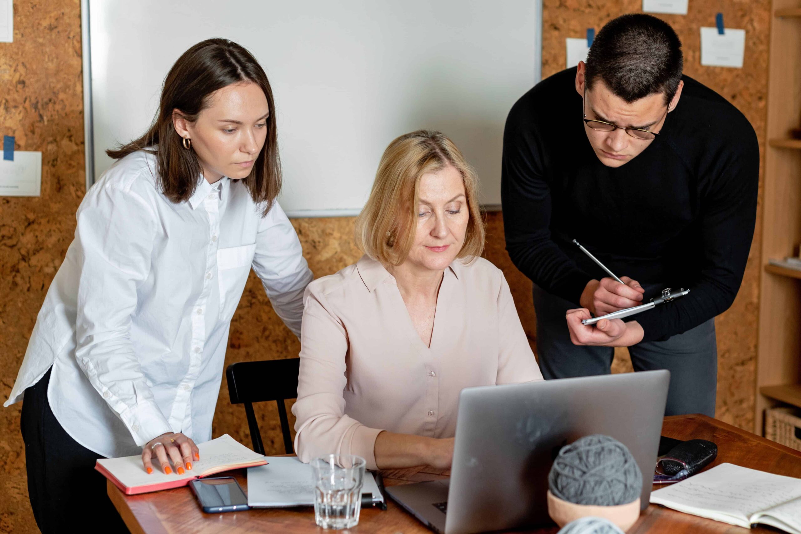 Three educators reviewing data together around a laptop during a professional learning session