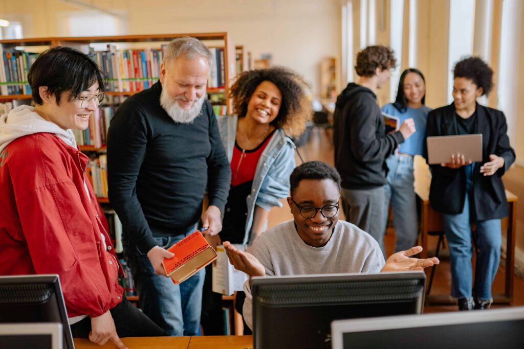 Diverse group of educators laughing and collaborating together in a school library